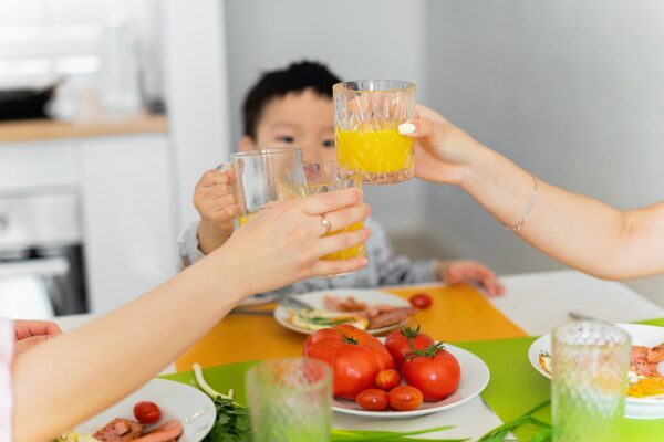 two women and boy toasting with glasses of juice during dinner